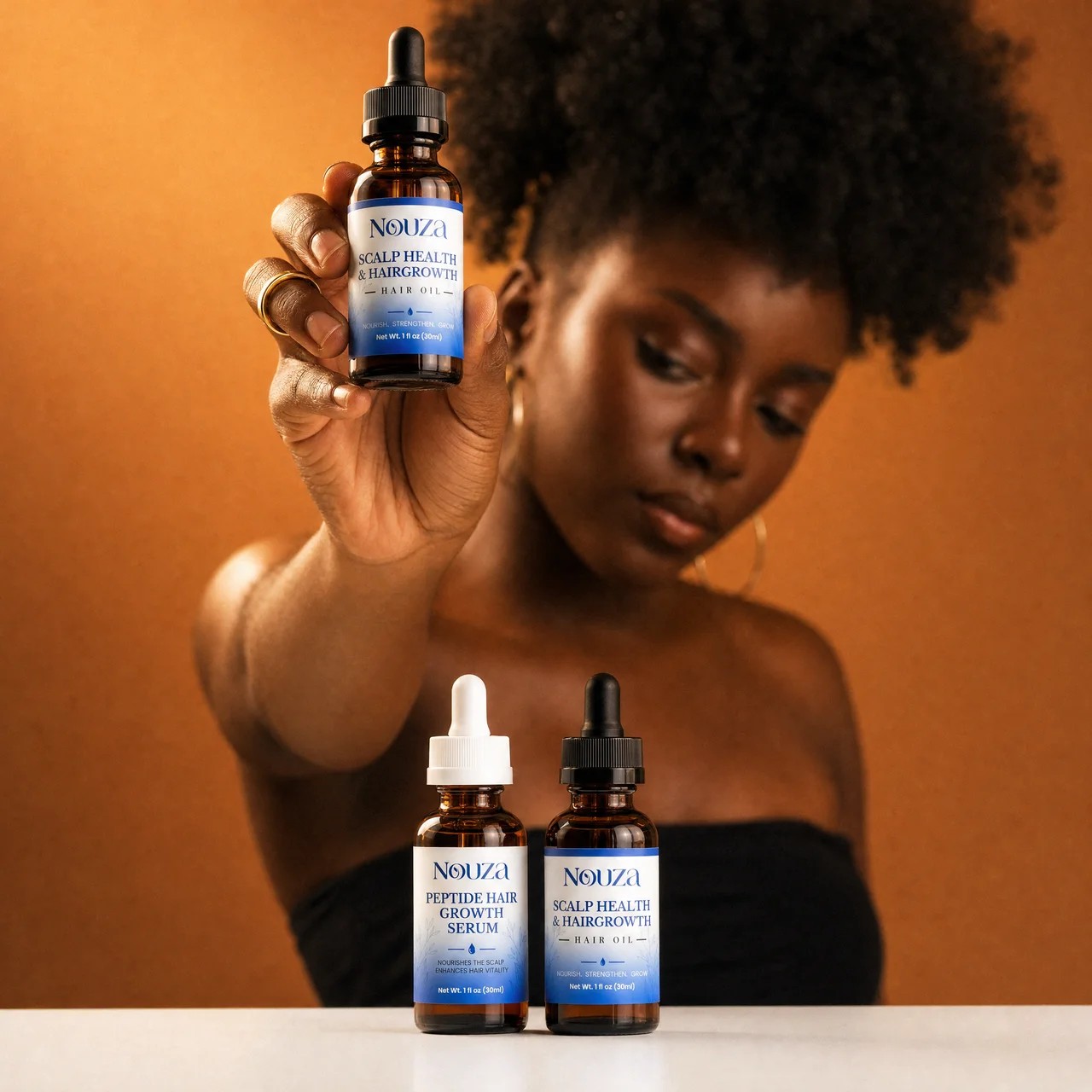 A woman holding the NOUZA Scalp Health & Hair Growth Oil with the Peptide Hair Growth Serum beside it
